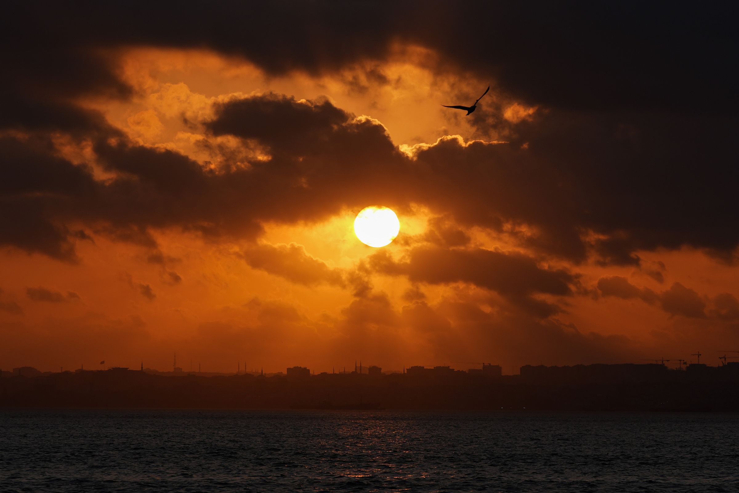 The sun shines through clouds at sunset.