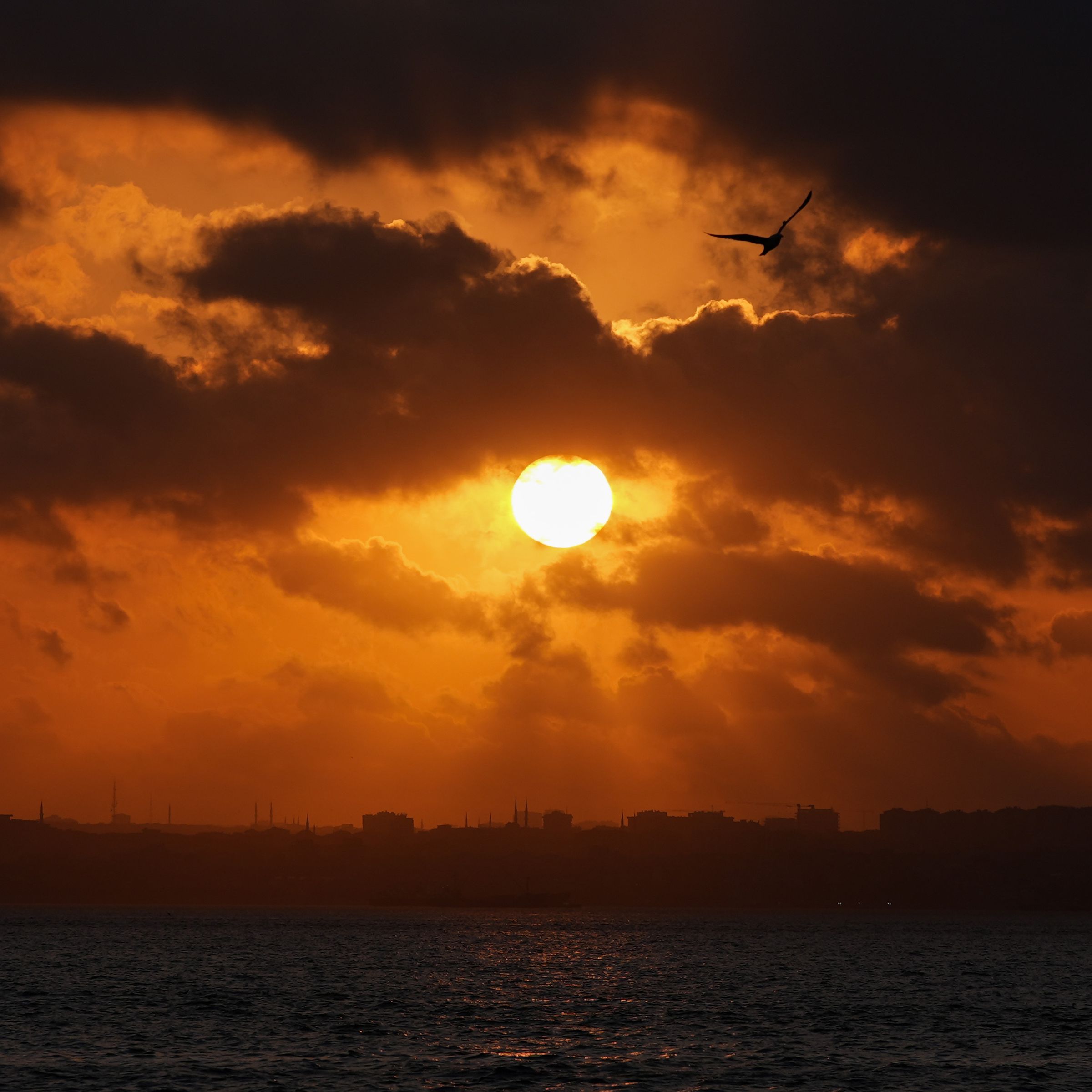 The sun shines through clouds at sunset.