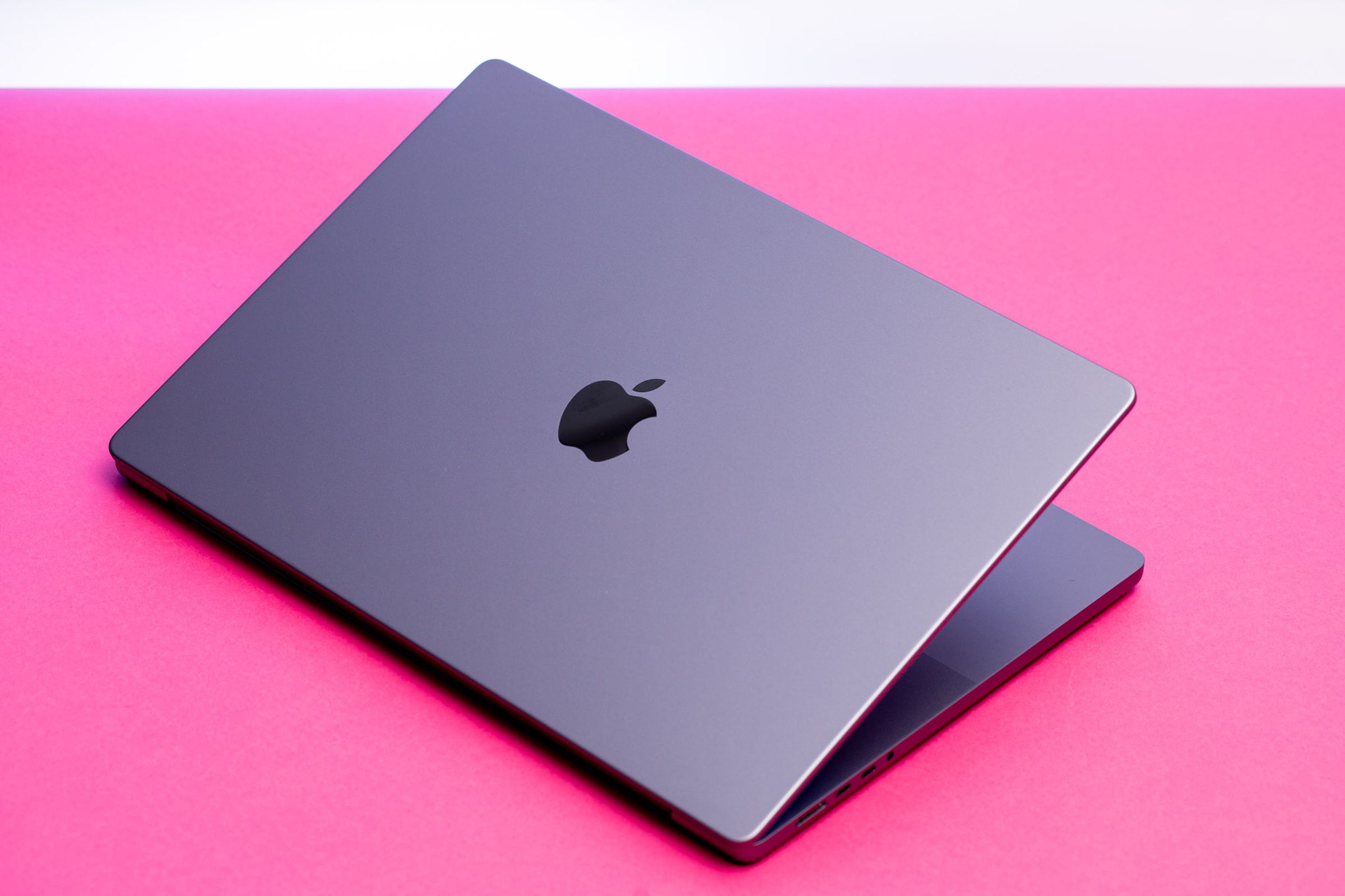 The MacBook Pro 16 half open seen from above on a pink table.