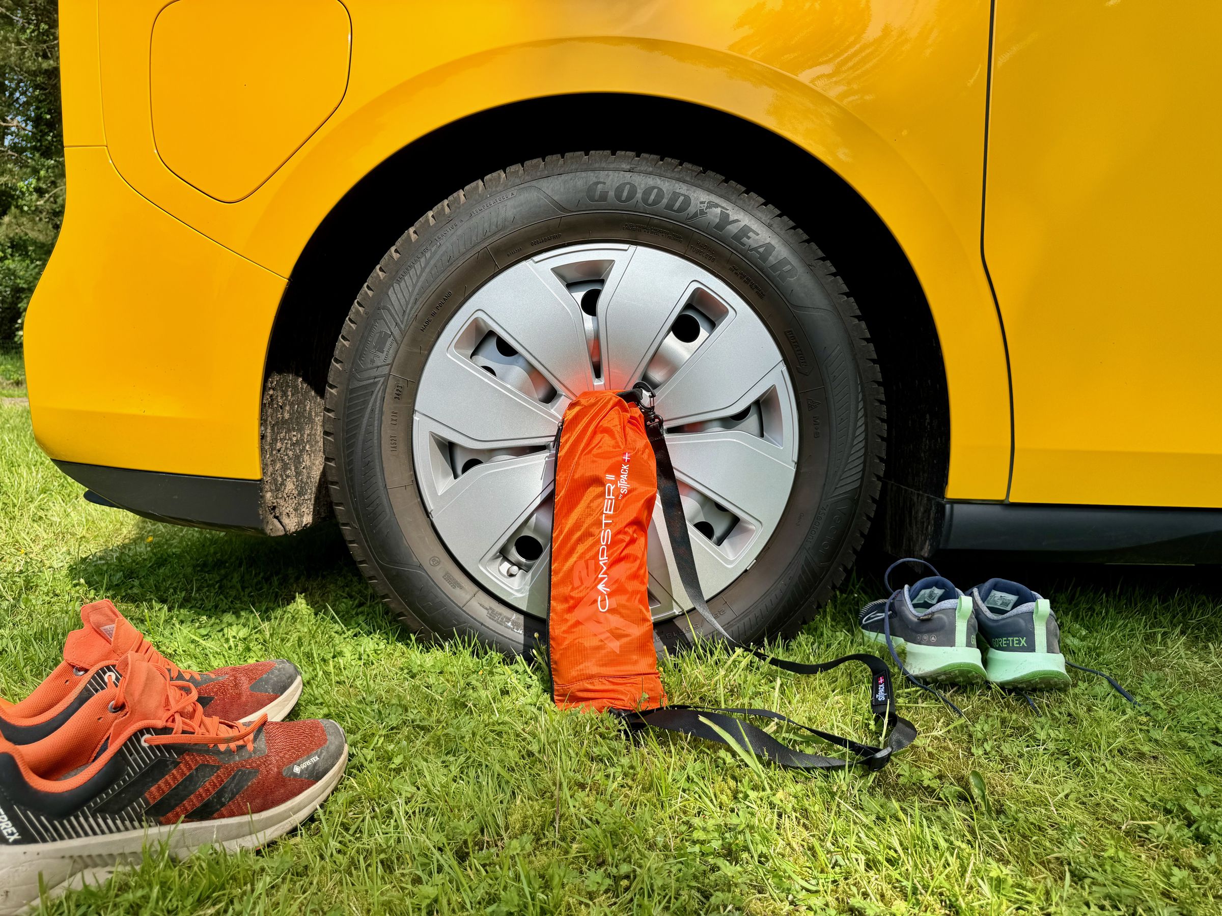 <em>Packed down into its carrying bag </em>— s<em>hoes of regular-sized humans for scale. Good for car camping or a day hike but too big / heavy for ultralight backpacking or bikepacking.</em>