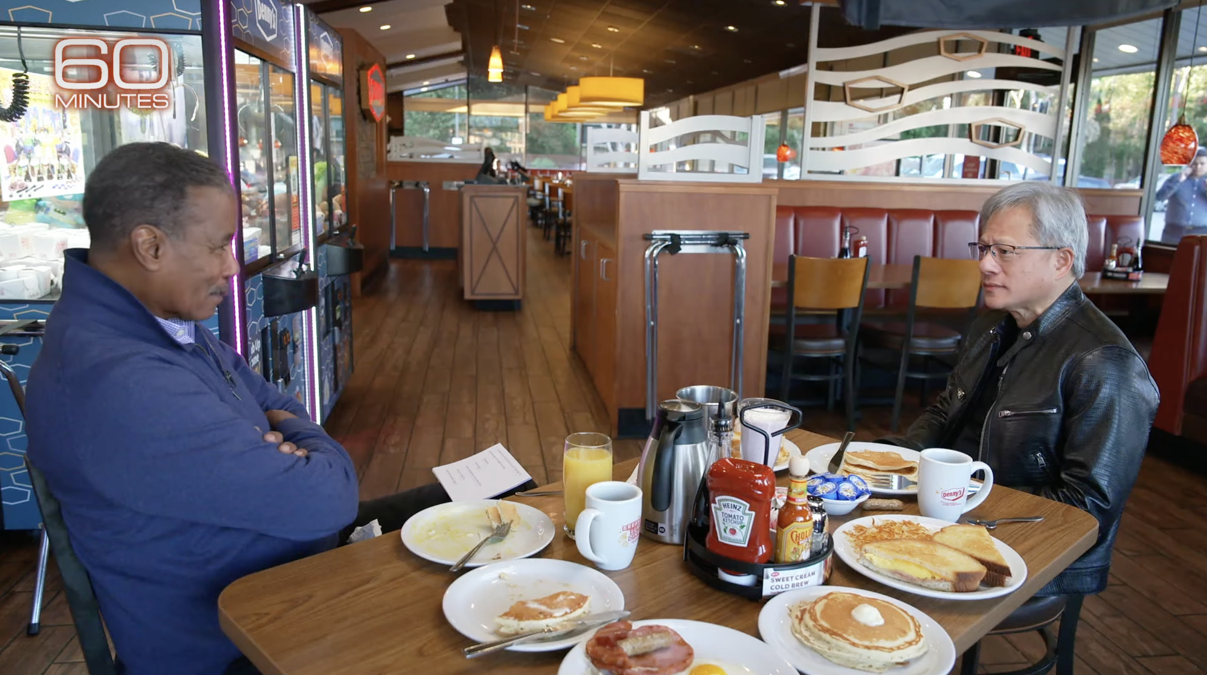 A screenshot of 60 Minutes’ Bill Whitaker and Nvidia’s Jensen Huang at Denny’s.